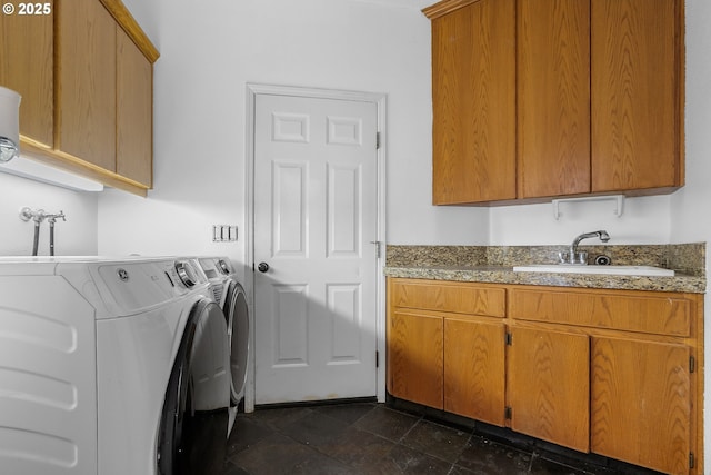 clothes washing area featuring a sink, washing machine and clothes dryer, and cabinet space