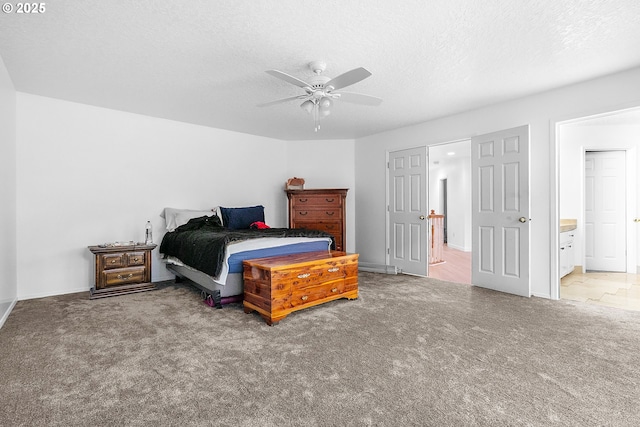 carpeted bedroom featuring a textured ceiling, connected bathroom, baseboards, and a ceiling fan