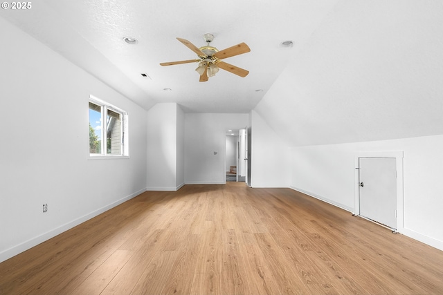 additional living space featuring vaulted ceiling, light wood-style flooring, baseboards, and ceiling fan