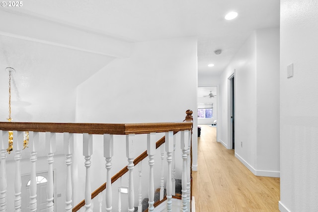 hallway featuring light wood finished floors, an upstairs landing, baseboards, and recessed lighting