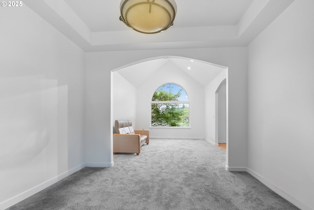 sitting room featuring carpet flooring, vaulted ceiling, baseboards, and arched walkways
