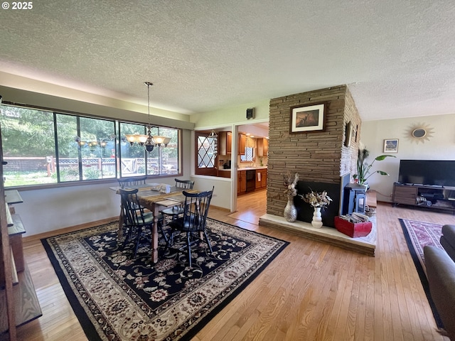 54824 Robinson Rd, Coquille, OR 97423 - dining space featuring a textured ceiling, a chandelier, light wood-style flooring, and a fireplace