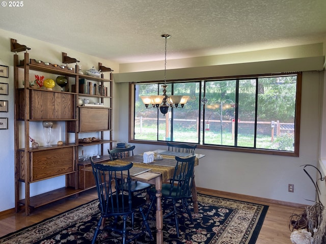 54824 Robinson Rd, Coquille, OR 97423 - dining area featuring a textured ceiling, wood finished floors, a chandelier, and baseboards