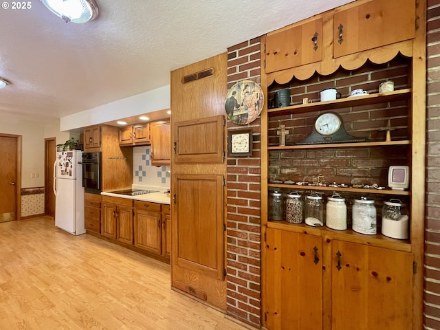 54824 Robinson Rd, Coquille, OR 97423 - kitchen with black appliances, light wood-style flooring, brown cabinets, decorative backsplash, and light countertops