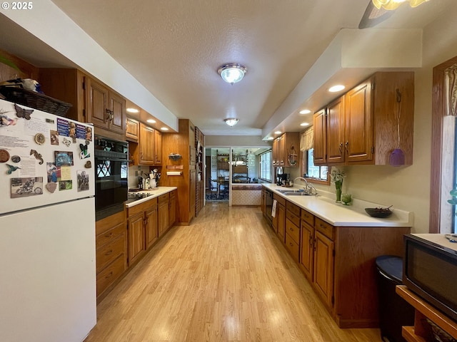 54824 Robinson Rd, Coquille, OR 97423 - kitchen featuring black appliances, a sink, brown cabinetry, light wood finished floors, and a textured ceiling