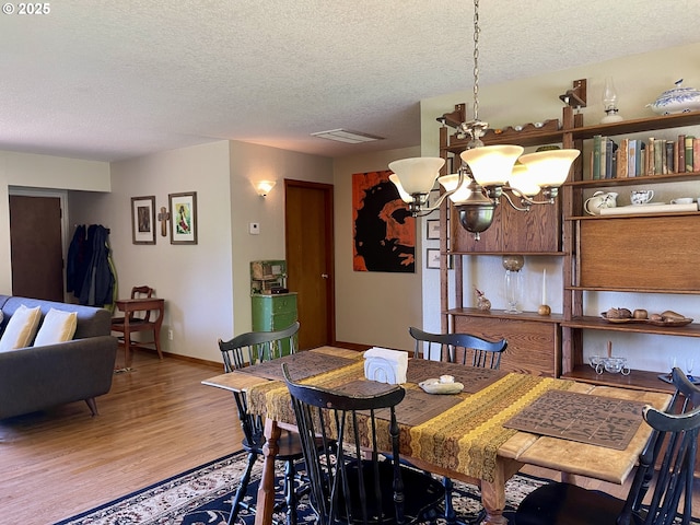 54824 Robinson Rd, Coquille, OR 97423 - dining area featuring a textured ceiling, a chandelier, light wood-style flooring, and baseboards