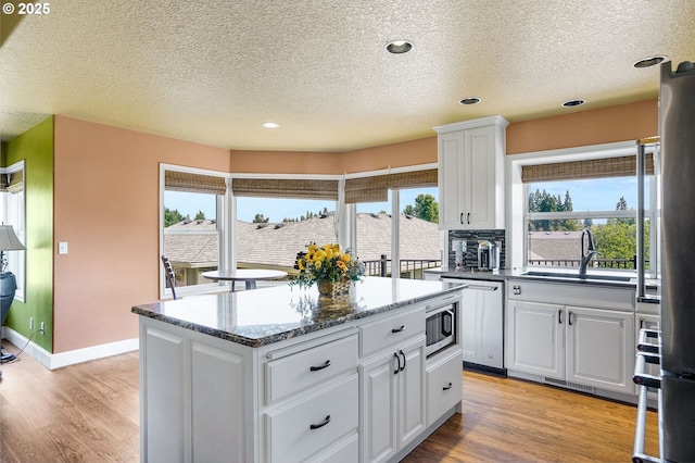 80 Sweden Cir, Silverton, OR 97381 - kitchen with a textured ceiling, a center island, plenty of natural light, light wood finished floors, and white cabinets