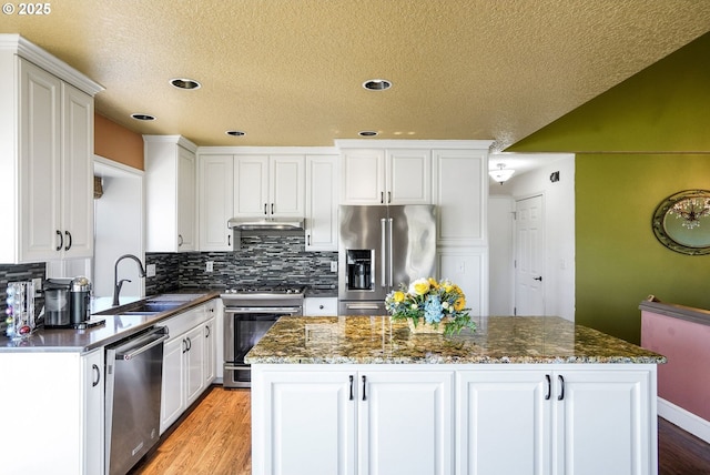 80 Sweden Cir, Silverton, OR 97381 - kitchen featuring stainless steel appliances, a center island, light wood-style floors, white cabinets, and tasteful backsplash