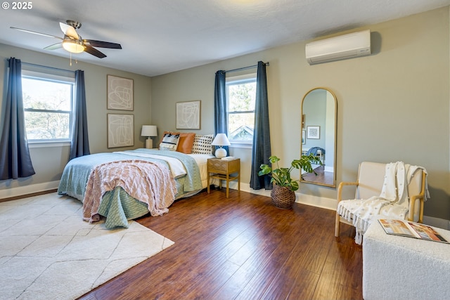 bedroom with hardwood / wood-style flooring, ceiling fan, multiple windows, and an AC wall unit