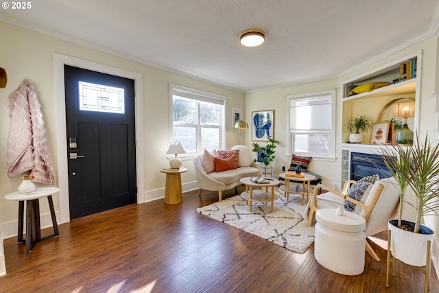 living room with crown molding, dark wood-type flooring, a fireplace, and a wealth of natural light