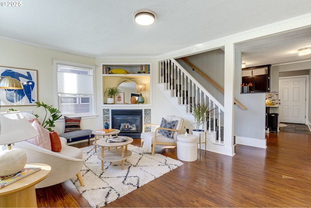 living room with a tiled fireplace, ornamental molding, and dark hardwood / wood-style floors