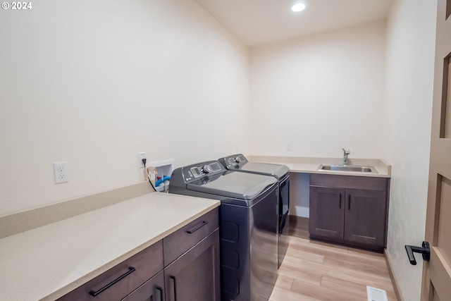 washroom featuring sink, light wood-type flooring, cabinets, and separate washer and dryer