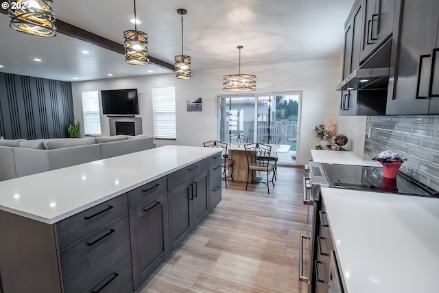 kitchen with decorative light fixtures, beam ceiling, plenty of natural light, and stainless steel electric range oven