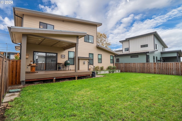 rear view of house with a deck and a yard