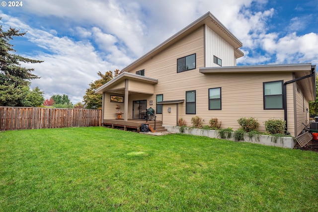 back of house featuring a wooden deck and a lawn