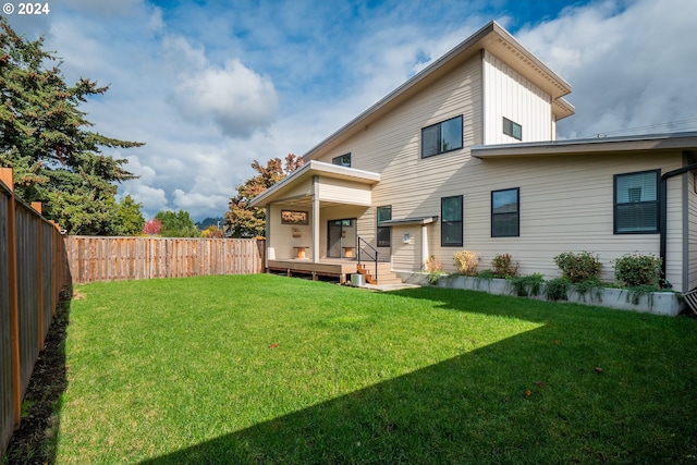 back of house featuring a lawn and a deck