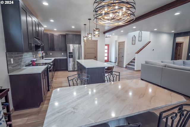 kitchen featuring pendant lighting, appliances with stainless steel finishes, a kitchen island, sink, and a breakfast bar area