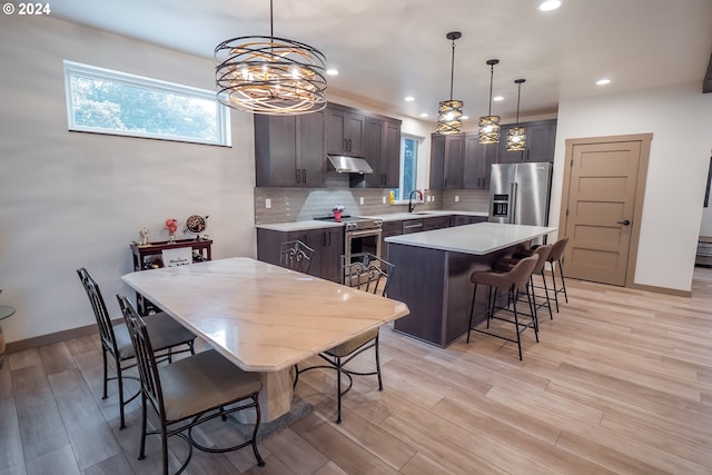 kitchen with sink, a kitchen island, pendant lighting, backsplash, and stainless steel appliances