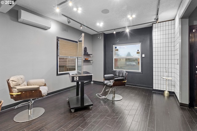 interior space with baseboards, a textured ceiling, an AC wall unit, and wood finished floors