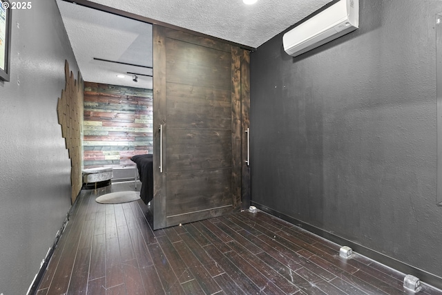 bathroom featuring a wall mounted air conditioner, a textured ceiling, wood finished floors, and a textured wall