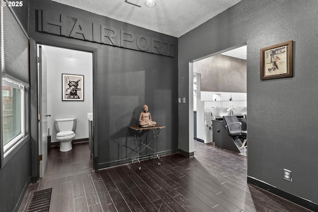 bathroom featuring visible vents, toilet, a textured ceiling, wood tiled floor, and a textured wall