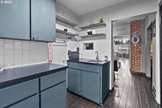 kitchen with dark wood-type flooring, a sink, open shelves, dark countertops, and a textured ceiling