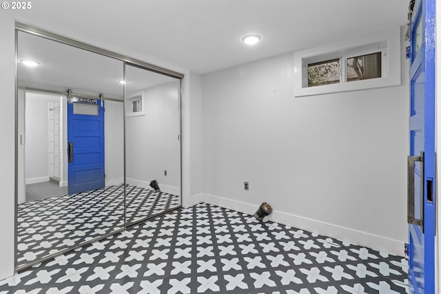 finished below grade area with tile patterned floors, baseboards, and a barn door