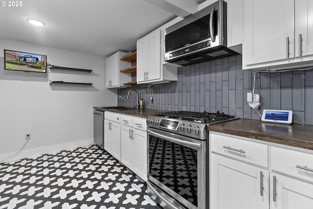 kitchen featuring baseboards, open shelves, a sink, appliances with stainless steel finishes, and backsplash