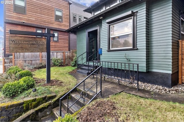 property entrance featuring fence and a lawn