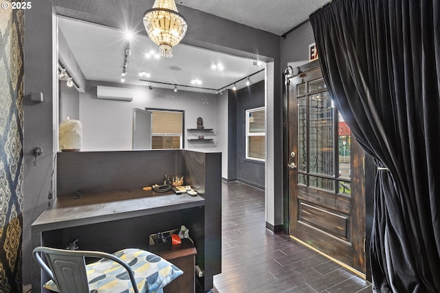 office with a wall unit AC, baseboards, wood finish floors, an inviting chandelier, and a textured ceiling