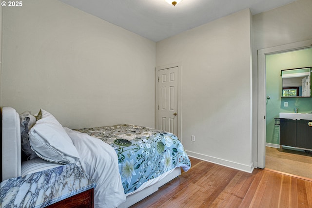 bedroom featuring baseboards, a sink, and light wood-type flooring