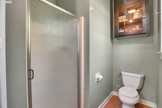 bathroom with baseboards, a stall shower, and toilet