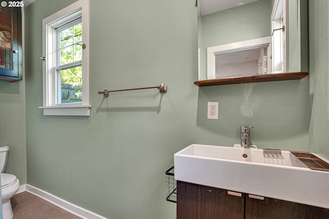 bathroom featuring toilet, baseboards, and vanity