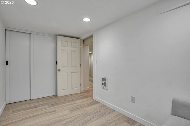 interior space with baseboards, a closet, light wood-style floors, heating unit, and recessed lighting