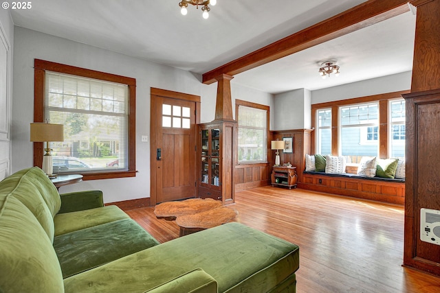 living room featuring a wainscoted wall, heating unit, wood finished floors, and beamed ceiling