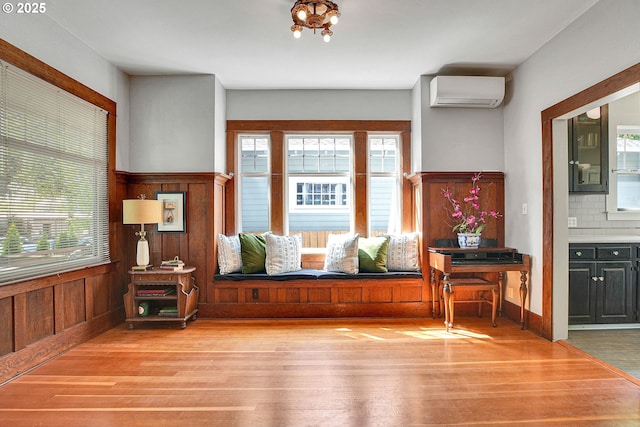 entrance foyer with wood finished floors, wood walls, wainscoting, and a wall unit AC