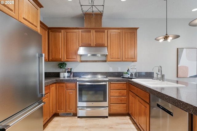 2452 NW Pettygrove St, Portland, OR 97210 - kitchen with exhaust hood, stainless steel appliances, light wood-style floors, dark countertops, and a sink