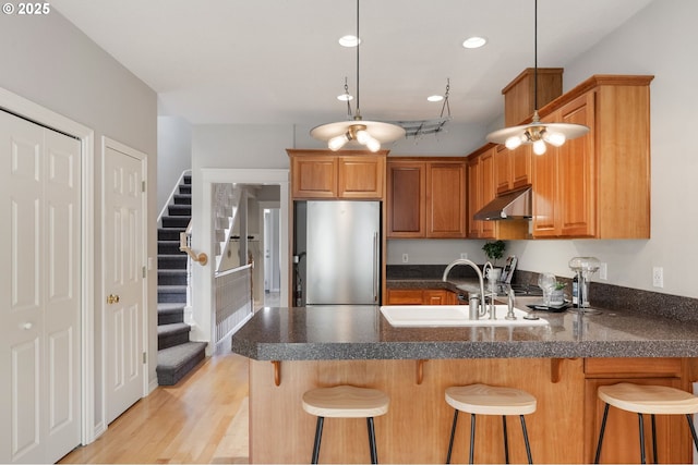 2452 NW Pettygrove St, Portland, OR 97210 - kitchen with a sink, under cabinet range hood, recessed lighting, stainless steel refrigerator, and a peninsula