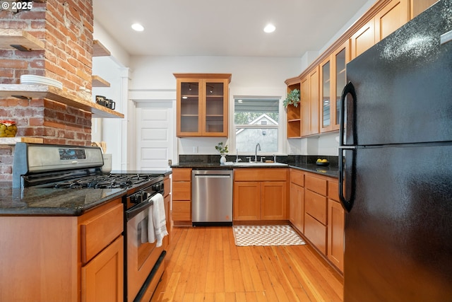 kitchen with open shelves, a sink, stainless steel appliances, glass insert cabinets, and light wood-style floors