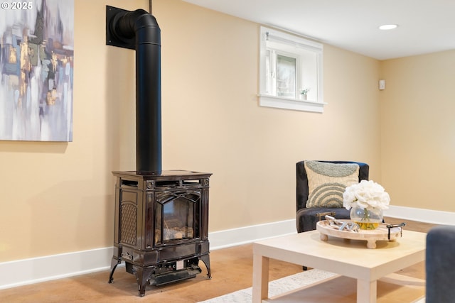 living area featuring recessed lighting, baseboards, and a wood stove