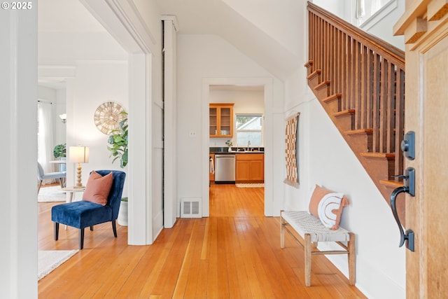 entrance foyer featuring light wood-type flooring, visible vents, and stairway