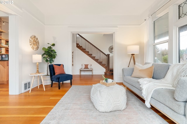 living room featuring visible vents, stairway, baseboards, and wood finished floors