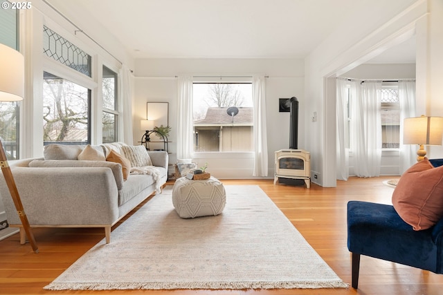 living room with a wood stove, plenty of natural light, and light wood-style floors