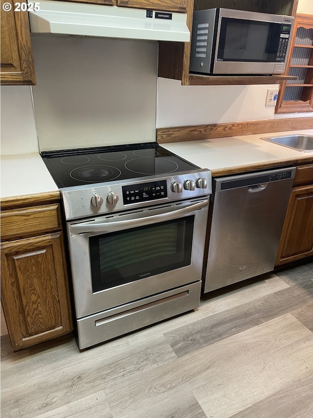 29815 NE 152nd Ave, Battle Ground, WA 98604 - kitchen featuring stainless steel appliances, under cabinet range hood, light wood finished floors, light countertops, and a sink