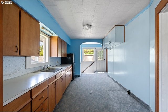 kitchen featuring a sink, light countertops, healthy amount of natural light, and arched walkways