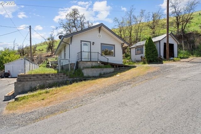 bungalow-style home with driveway and an outbuilding