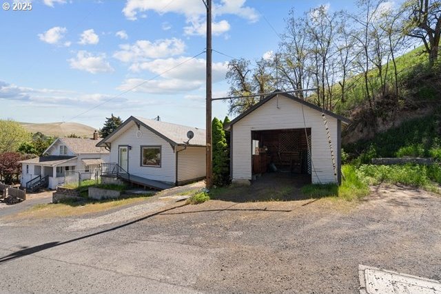 view of front of home with a garage, dirt driveway, and an outbuilding