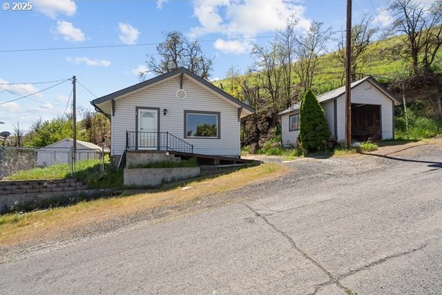 bungalow-style home with fence and an outdoor structure