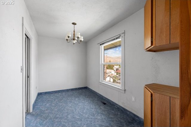 unfurnished dining area with a chandelier and carpet