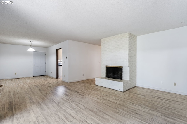 224 N Hayden Bay Dr, Portland, OR 97217 - unfurnished living room with light wood-style floors, a brick fireplace, and a textured ceiling